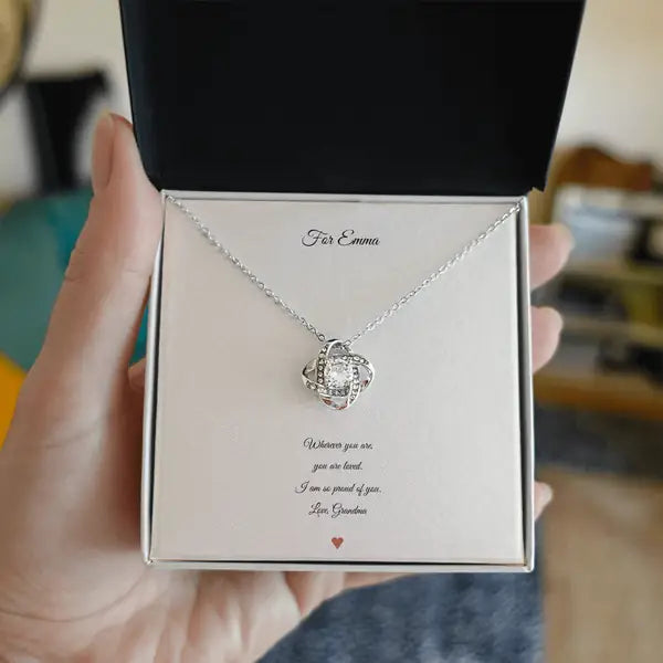 The open gift box held in a hand, with the card and the necklace inside